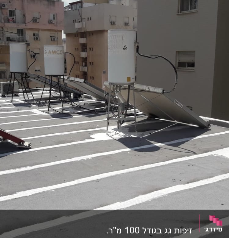 קווים לבנים של איטום על גג שטוח עם דודי שמש